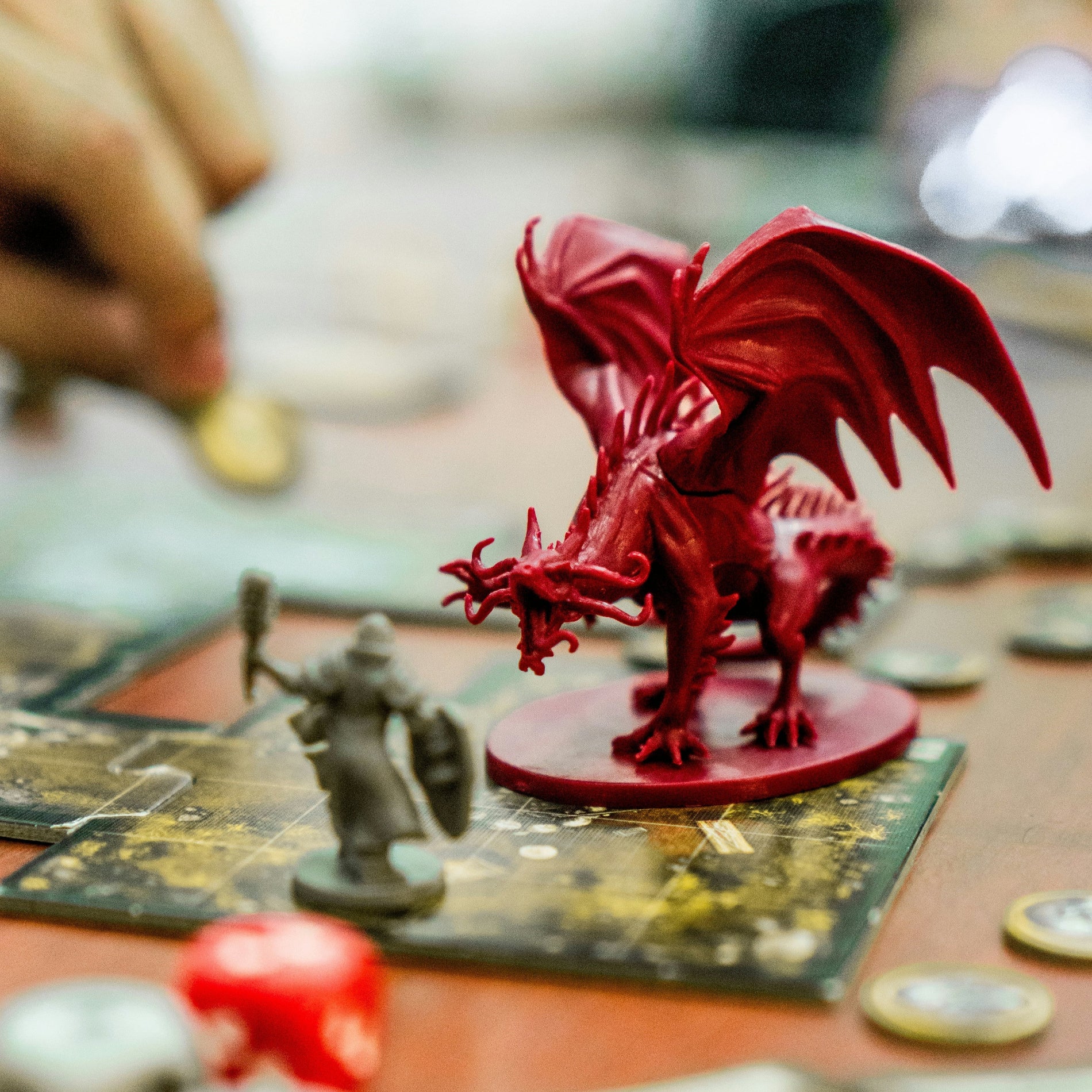 Red dragon figurine on a board game with players in the background